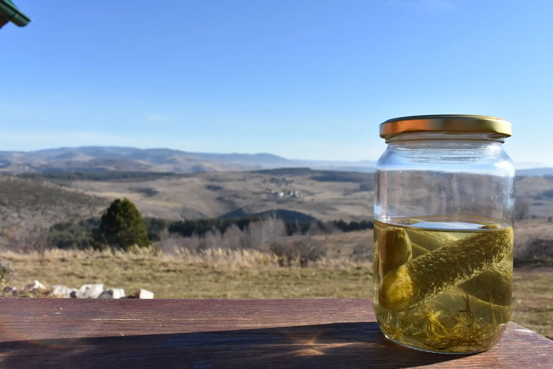 a jar of pickles on a table looking over a mountain view